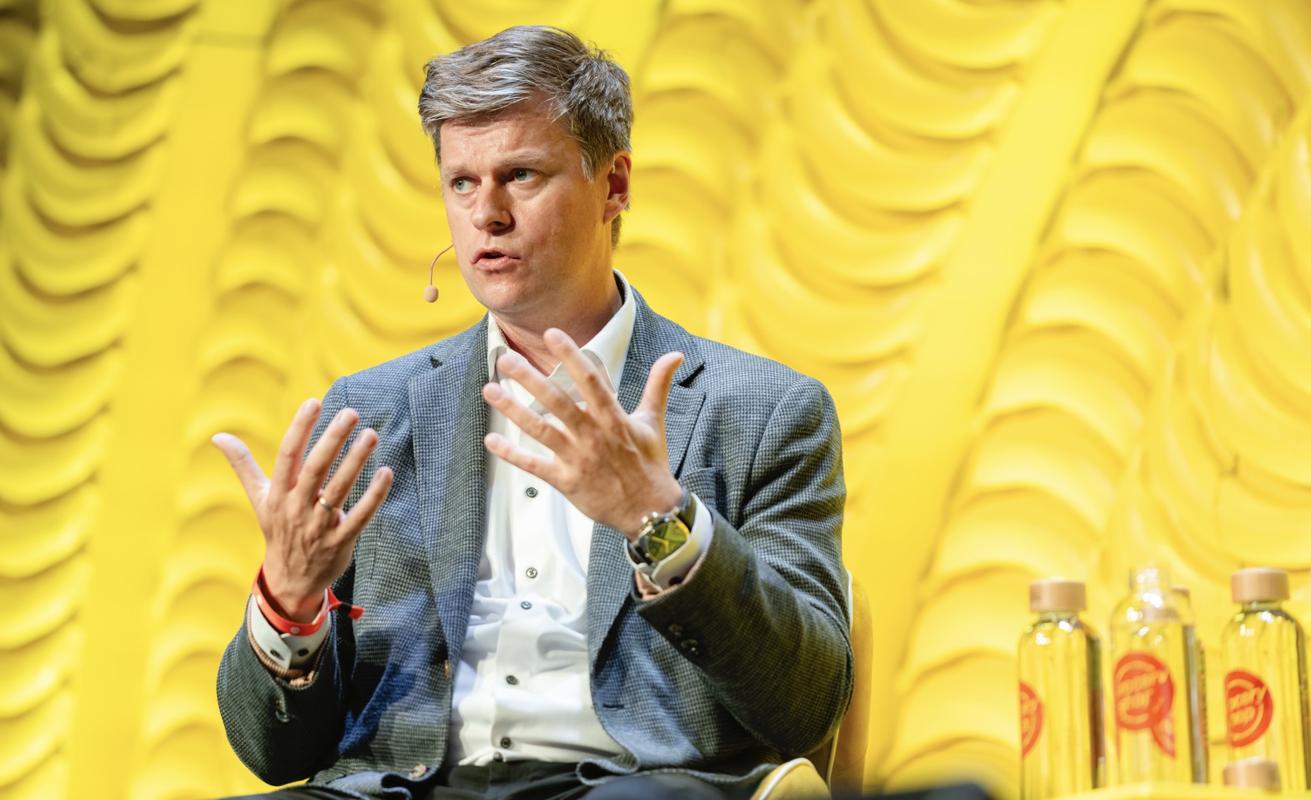 A person in a suit with microphone AI-generated content may be incorrect.